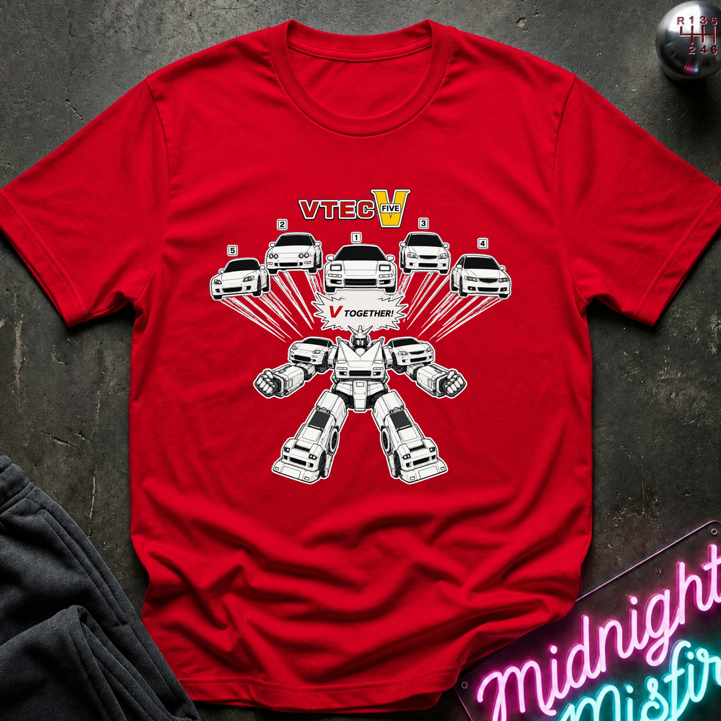 A red short-sleeve crewneck t-shirt laid flat on a dark textured surface. The shirt features a graphic of white cars transforming into a robot-like vehicle design with the text 'V TOGETHER' and 'VTECH' in yellow.