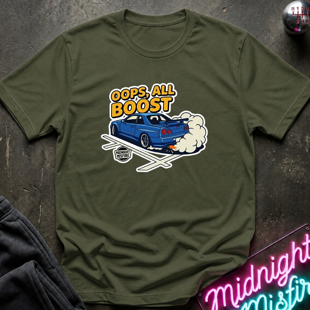 An olive green short-sleeve t-shirt with a graphic of a blue race car and the text 'OOPS, ALL BOOST' in yellow and white, laid flat on a dark textured surface.