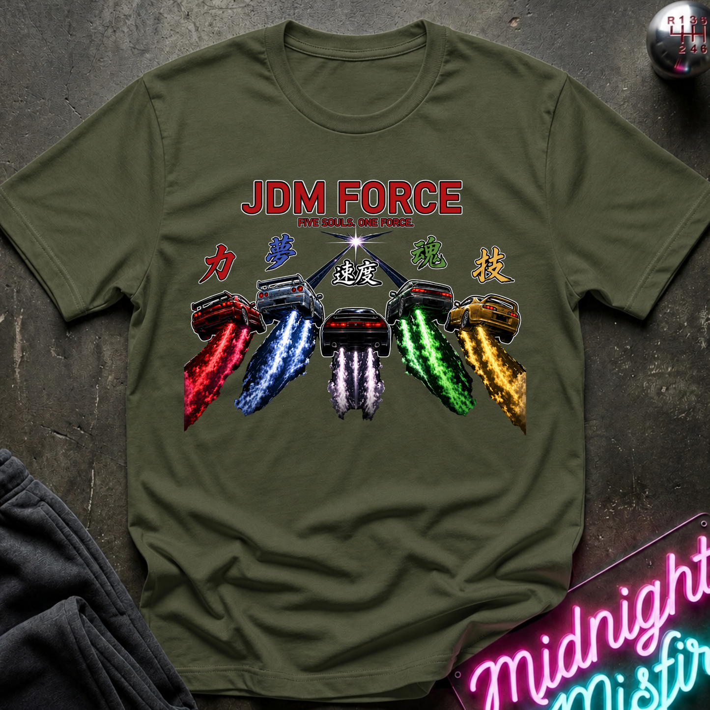An olive green short-sleeve t-shirt with a graphic print of six DeLorean time machines from the Back to the Future franchise, each leaving a colorful exhaust trail. The text 'JDM FORCE' is printed in red above the machines, with Japanese characters integrated into the design.