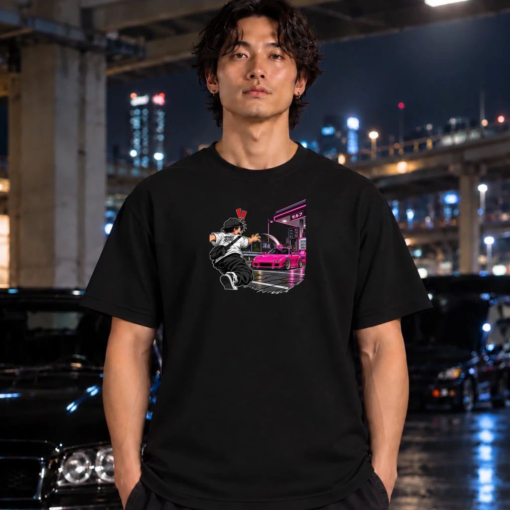 man wearing a black t-shirt and the center of the shirt features a graphic print of an anime character in a black and white outfit with a hat, next to a sports car
