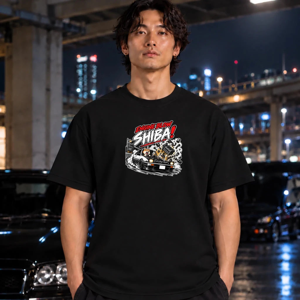 man wearing black short-sleeve graphic t-shirt featuring a stylized graphic of a white sports car with a glowing engine and the text 'ENGINE BLOW SHIBA!' in red, white, and black.