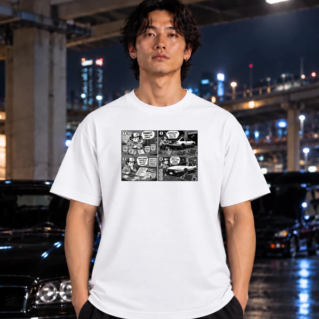 A man wearing a white short-sleeve t-shirt with a black and white comic book panel graphic on the chest, standing in front of a blurred nighttime city background with cars.