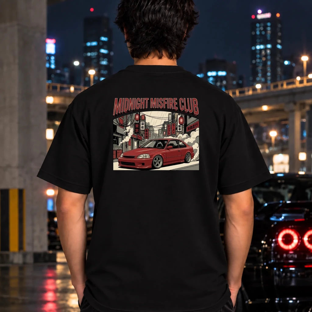 A man viewed from behind wearing a black t-shirt with a large graphic print on the back. The graphic features the text 'MIDNIGHT MISFIRE CLUB' in red and black, above an illustration of a red sports car drifting in a city street at night.