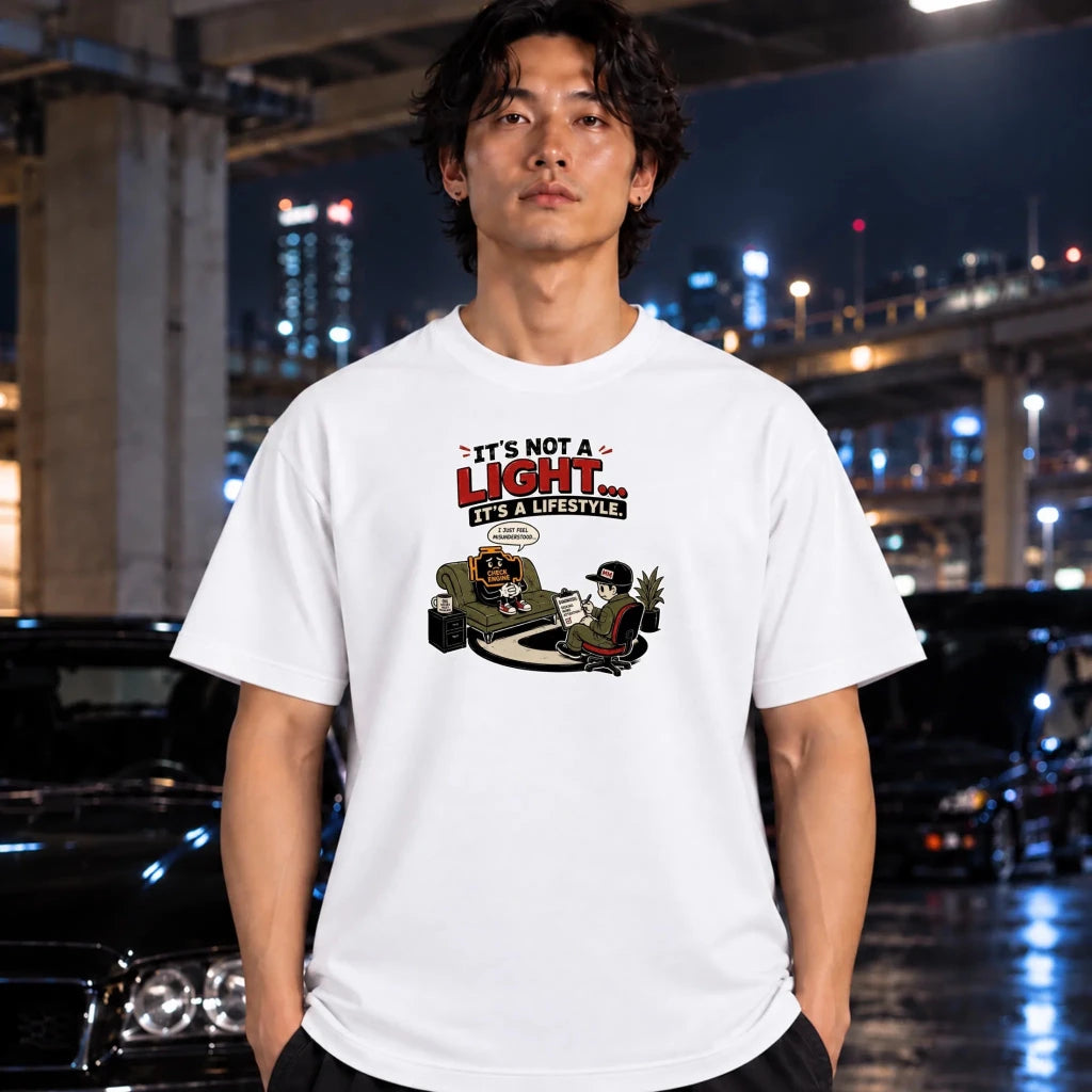 A man wearing a white graphic t-shirt with a cartoon design and the text 'IT'S NOT A LIGHT.