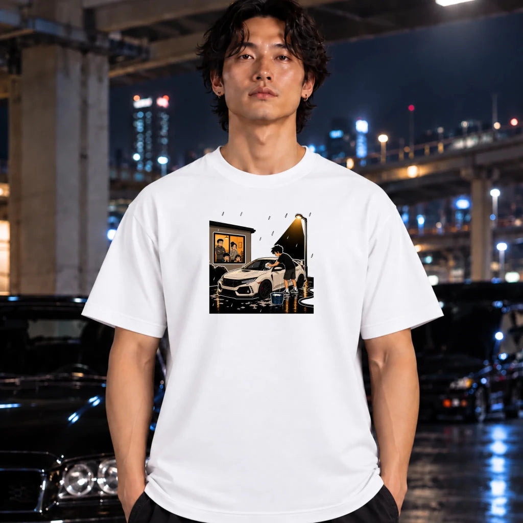 A man wearing a white graphic t-shirt with a car-themed print, standing in a wet urban night setting with cars and city lights in the background.