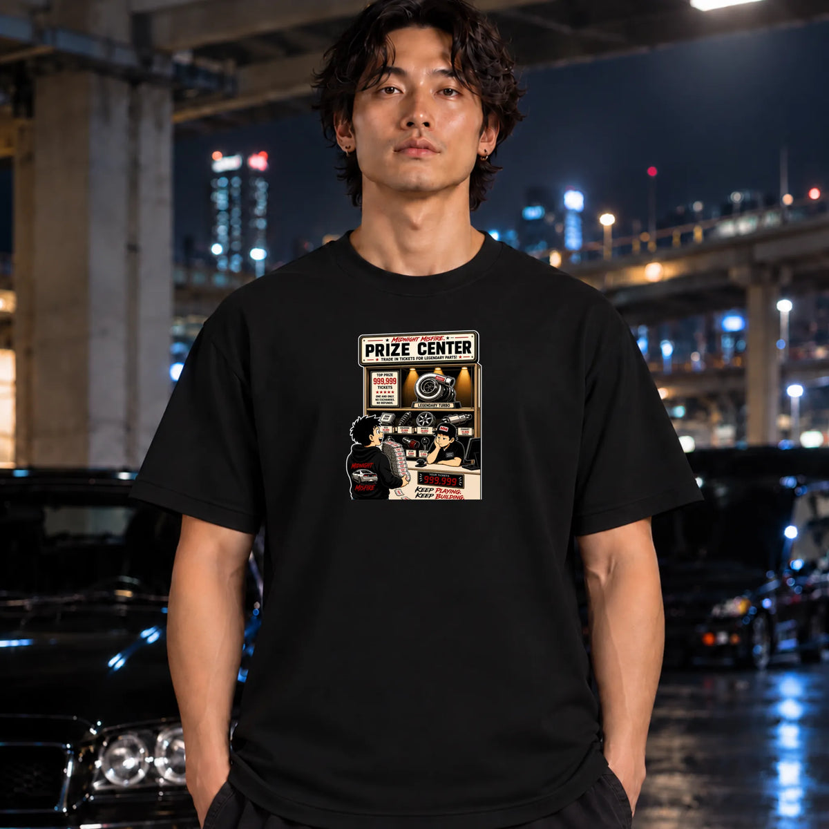 man wearing a black short-sleeve graphic t-shirt. The graphic on the front depicts a retro-style poster for a 'Prize Center' with a person holding a trophy and warm spotlight tones.