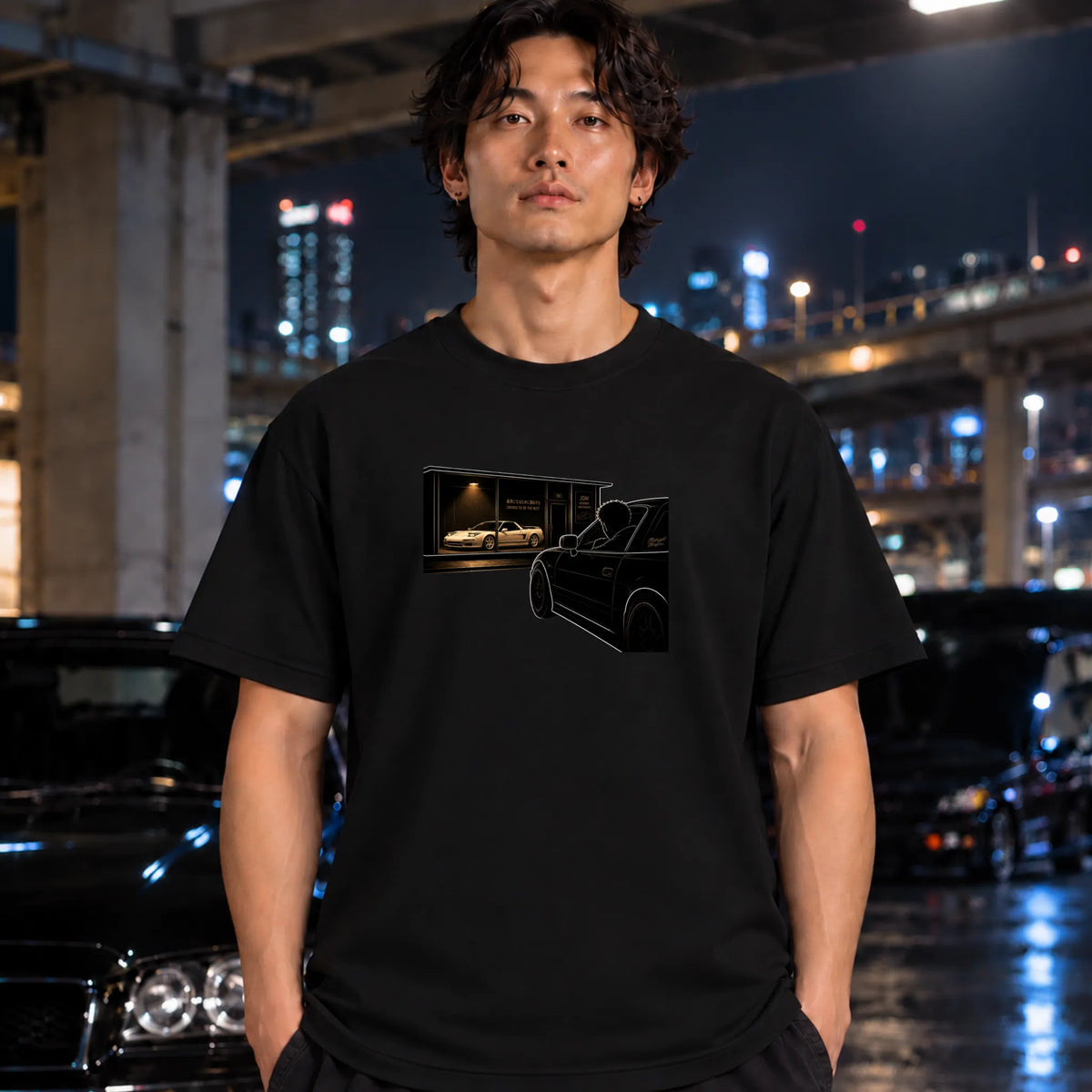 man wearing black t-shirt featuring a graphic print of a black car silhouette in front of a garage with a white car inside.