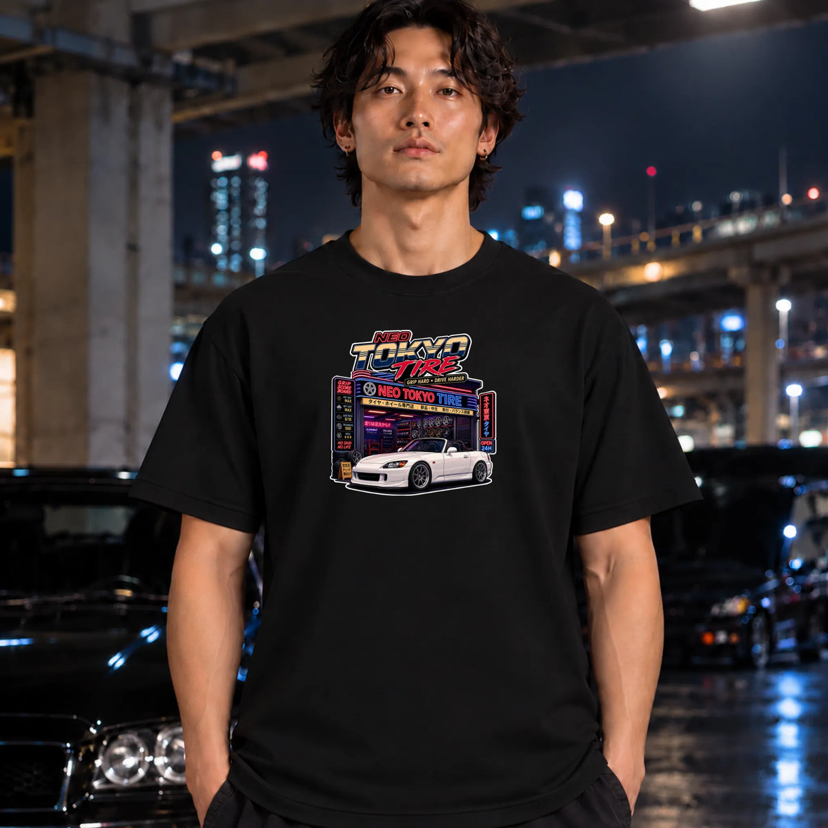 man wearing black short-sleeve t-shirt with a colorful graphic print of a 'Neo Tokyo Tire" arcade and a black sports car,
