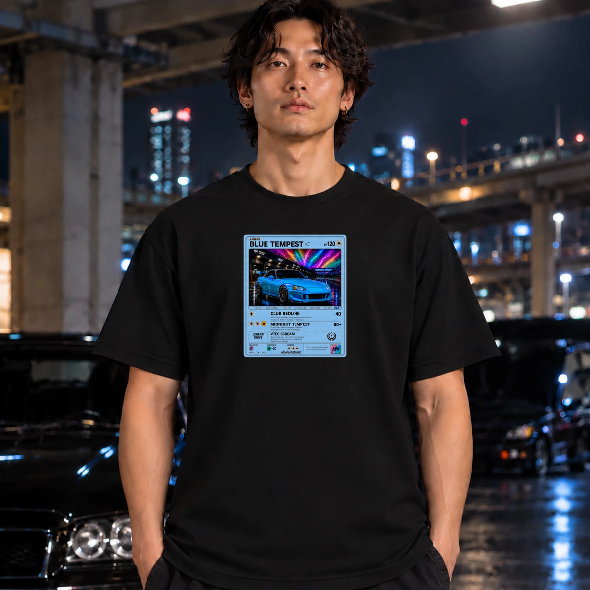 A man wearing a black t-shirt with a retro-style Pokémon card graphic that reads 'BLUE TEMPEST.