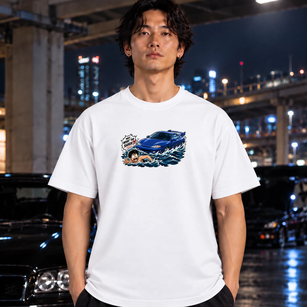 A white short-sleeved t-shirt that has a blue car chasing a swimmer in open water worn by a man.