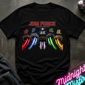 A black short-sleeve graphic T-shirt laid flat on a dark textured surface. The shirt features a colorful chest print with the words 'JDM FORCE' in red, 5 cars with glowing colored exhaust trails, and stylized characters.
