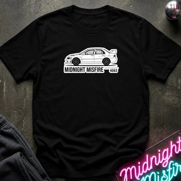 black short-sleeve t-shirt laid flat on a dark textured surface, featuring a white sports car graphic and the text 'MIDNIGHT MISFIRE '