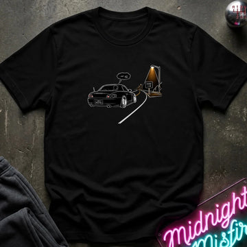 A black short-sleeve t-shirt laid flat on a dark textured surface, featuring a graphic print of a black sports car driving passed sign that says home.