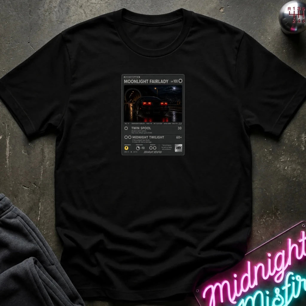 black crewneck t-shirt laid flat on a dark textured surface, featuring a graphic print of vintage card and a car.