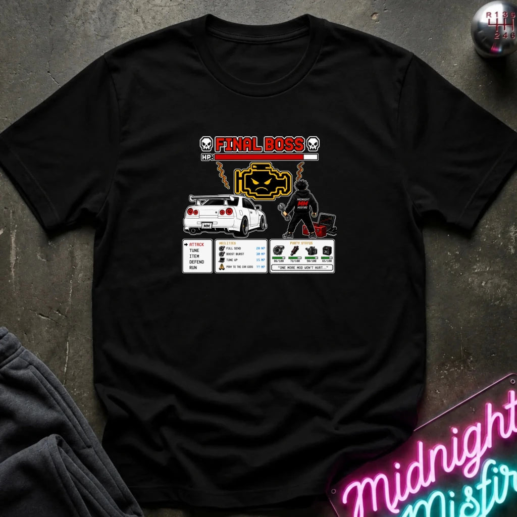 A black graphic t-shirt laid flat on a dark textured surface. The shirt features a 'Final Boss' engine design inspired by the rpg game.