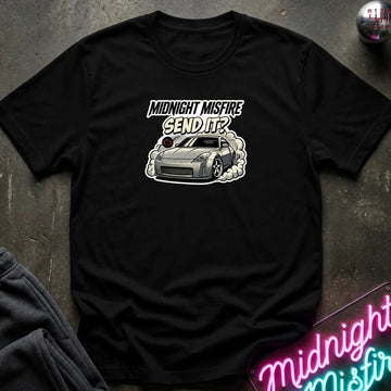 black short-sleeve t-shirt laid flat on a dark textured surface, featuring a graphic of a gray sports car with smoke and the text 'MIDNIGHT MISFIRE SEND IT?' printed on the chest.