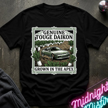 A black short-sleeve graphic T-shirt laid flat on a dark textured surface. The shirt features a large rectangular front print with the words 'GENUINE TOUGHE DAIKON' and 'GROWN IN THE APEX'.