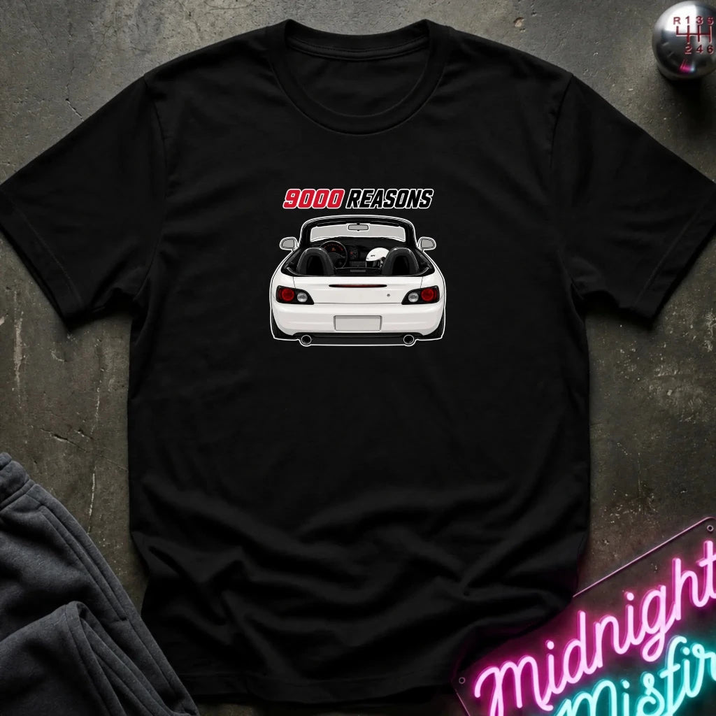 A black short-sleeve graphic t-shirt laid flat on a dark textured surface. The shirt features a white convertible sports car graphic with the text '9000 REASONS' in red and white above it.