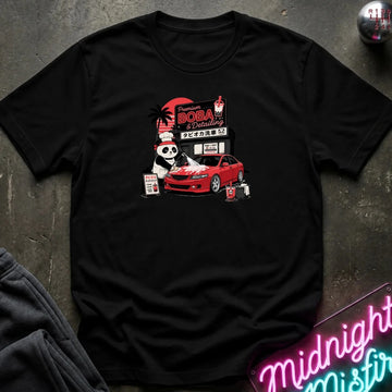A black short-sleeve graphic t-shirt laid flat on a dark textured surface. The graphic features a cartoon panda wearing a hat next to a red sports car, with a sign reading 'Midnight Boba'.