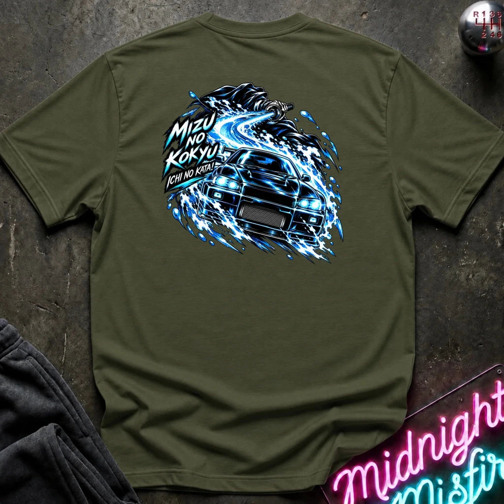 An olive green t-shirt laid flat on a dark textured surface, featuring a large graphic print of a black sports car surrounded by blue electric spark effects and Japanese text. A folded pair of dark jeans and a neon sign are partially visible in the corners.