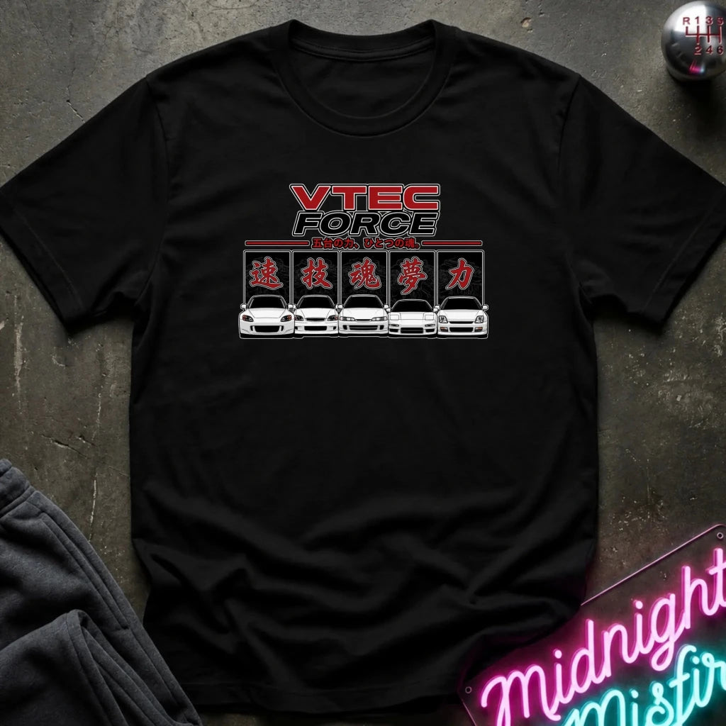 A black short-sleeve graphic t-shirt laid flat on a dark textured surface. The graphic features the text 'VTEC FORCE' in red and white, followed by Japanese katakana characters and a row of white sports cars.