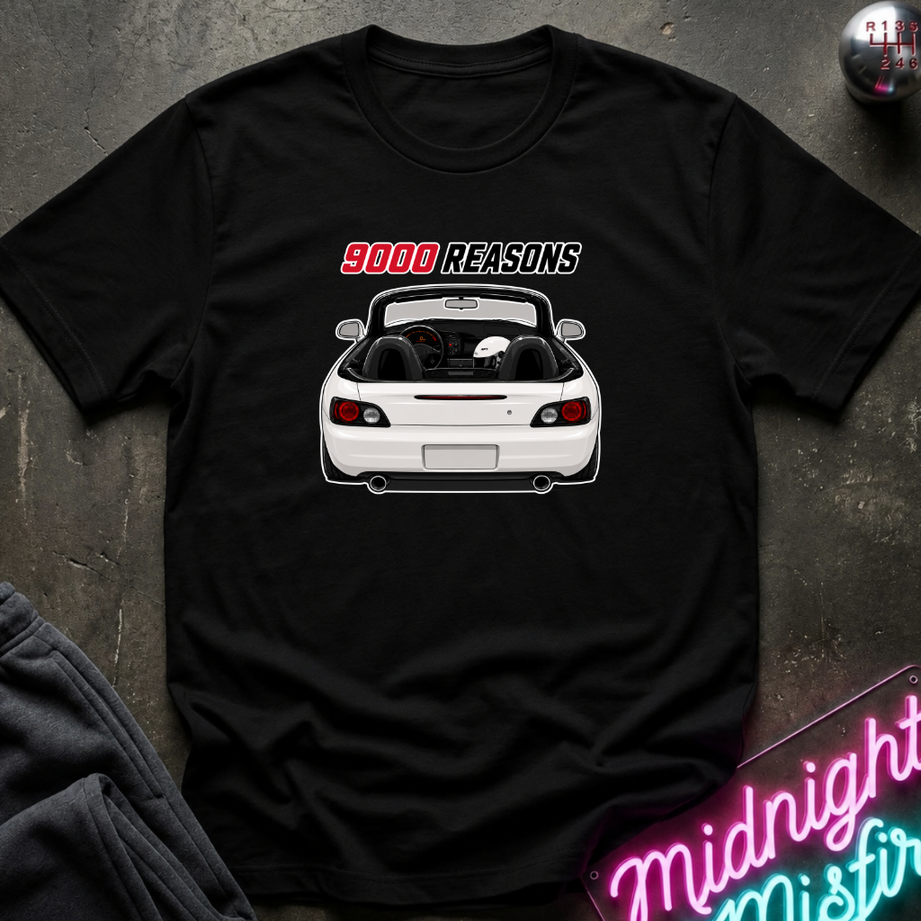 A black short-sleeve graphic t-shirt laid flat on a dark textured surface. The shirt features a white convertible car graphic with the text '9000 REASONS' in red and white above it.