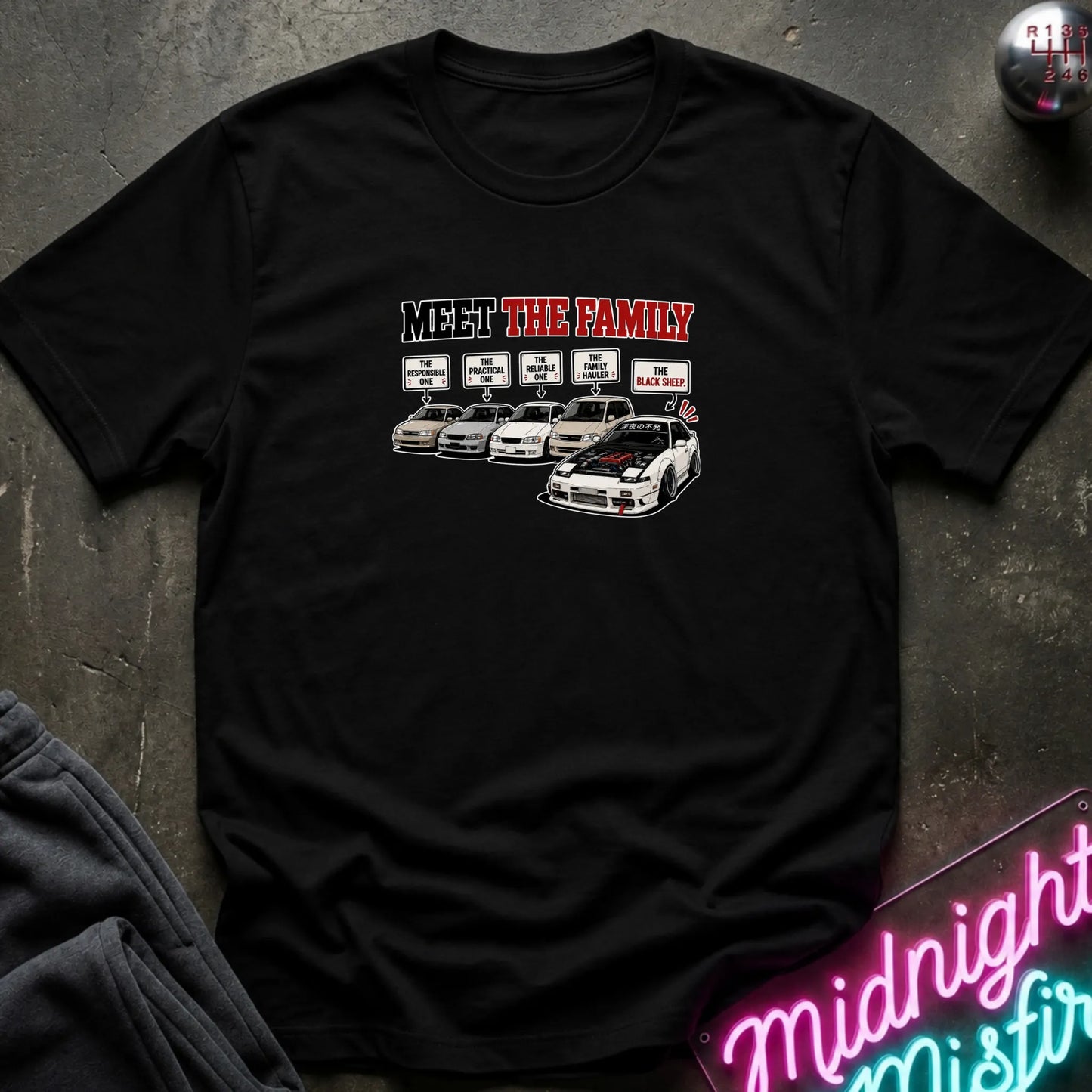 A black short-sleeved t-shirt  that has a cars parked with one standing out that says black sheep.