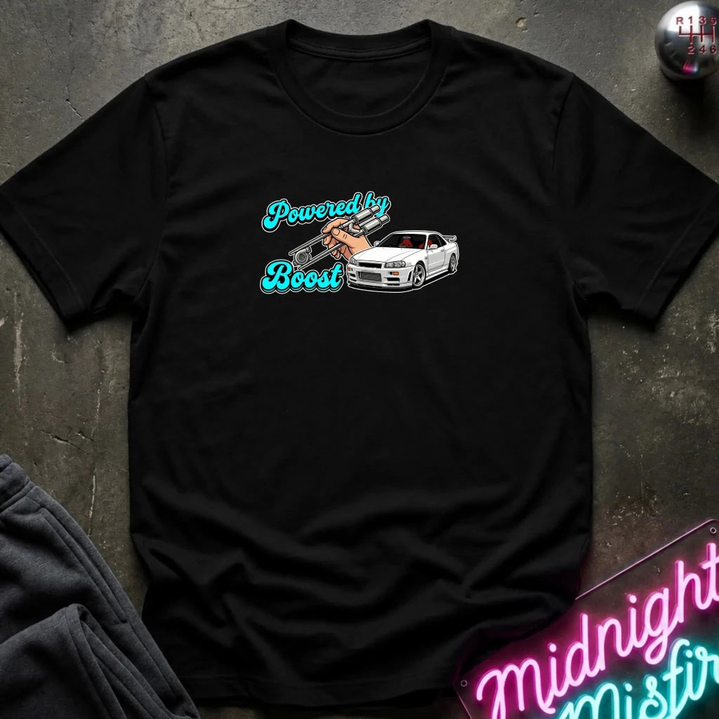 A black short-sleeve graphic t-shirt laid flat on a dark textured surface. The graphic features the text 'Powered by Boost' in a stylized blue font, with a hand holding a car engine block, next to a white sports car.
