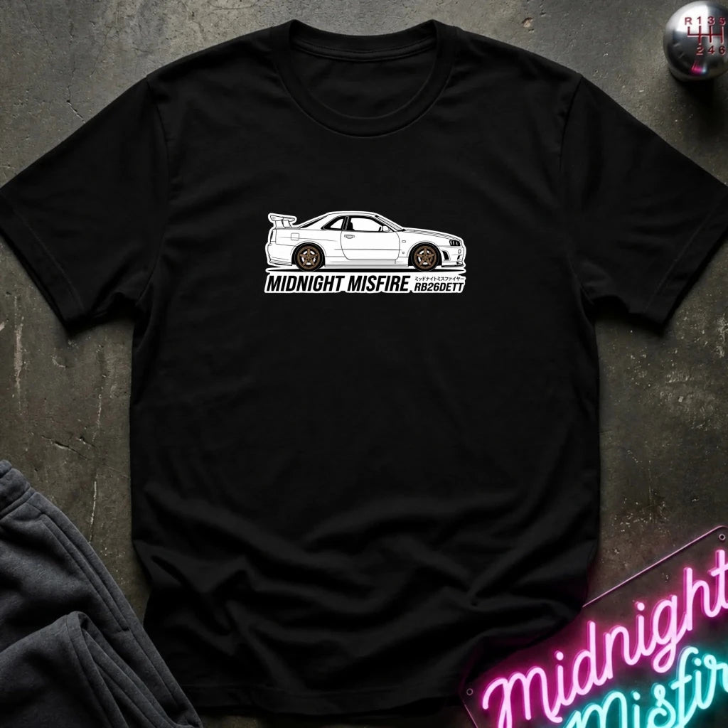 black short-sleeve t-shirt laid flat on a dark textured surface, featuring a white sports car graphic and the text 'MIDNIGHT MISFIRE '