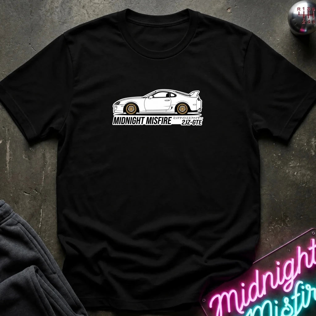 black short-sleeve t-shirt laid flat on a dark textured surface, featuring a white sports car graphic and the text 'MIDNIGHT MISFIRE '