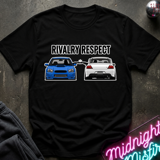 A black short-sleeve graphic T-shirt laid flat on a dark textured surface. The shirt features the words 'RIVALRY RESPECT' above an illustration of a blue car facing a white car