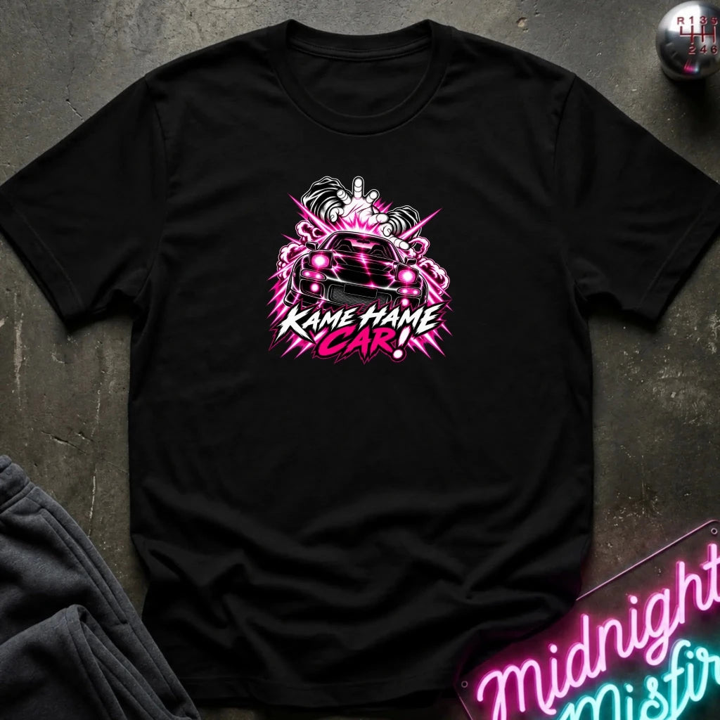black short-sleeve graphic t-shirt laid flat on a dark textured surface. The shirt features a red, white, and black graphic of a car with the text 'KAME HAME CAR!' in stylized lettering.