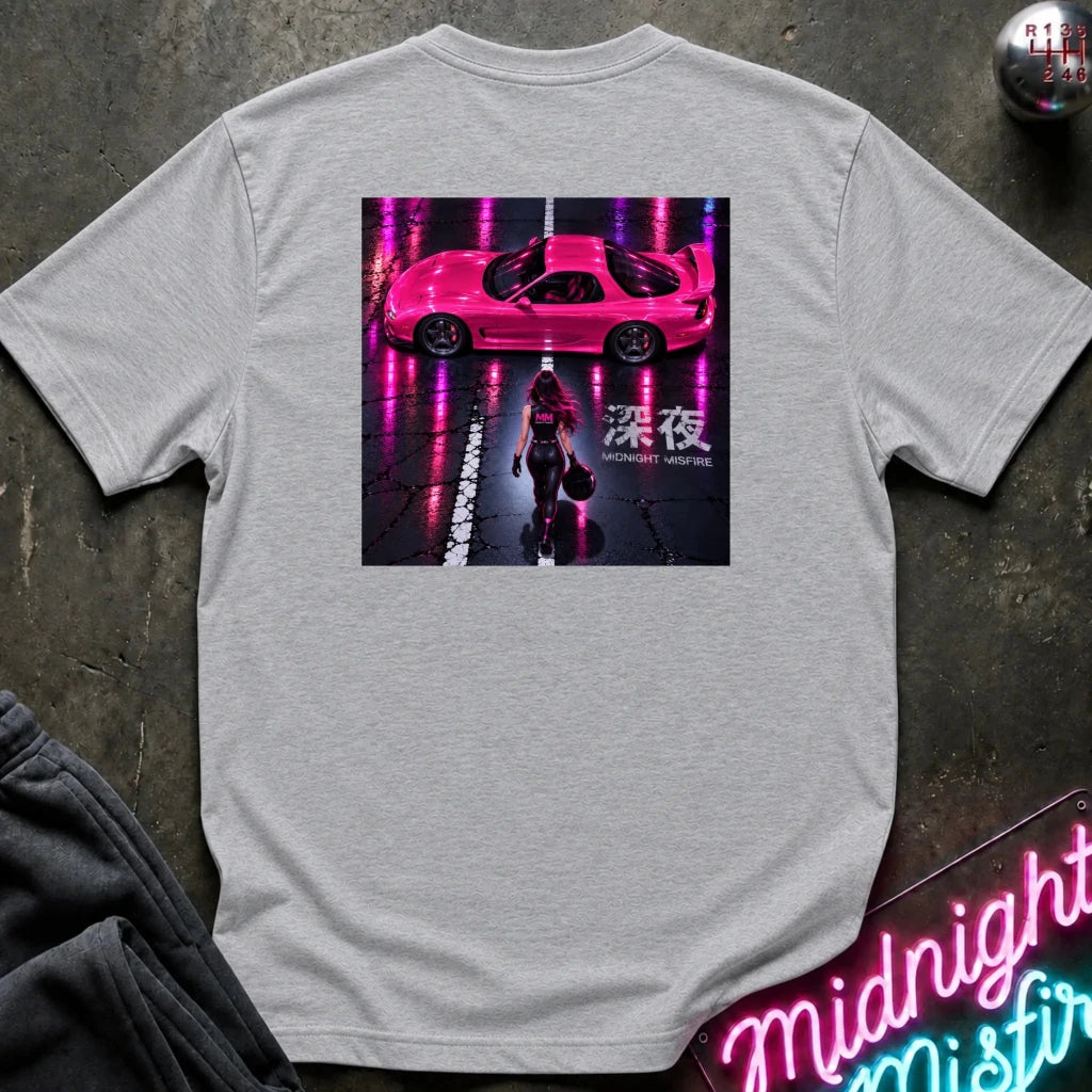 A light gray heather crewneck t-shirt laid flat on a dark textured surface. The shirt features a large rectangular graphic print on the front showing a pink sports car on a wet street with neon pink reflections and a woman walking, with Japanese characters
