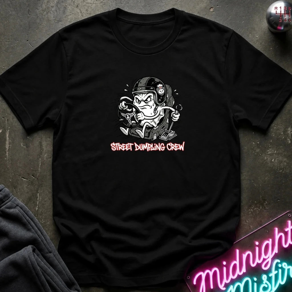 black crewneck t-shirt laid flat on a dark textured surface. The shirt features a graphic of a street-dumper character wearing a helmet and goggles, with the text 'STREET DUMPING CREW' printed below in a pink font.
