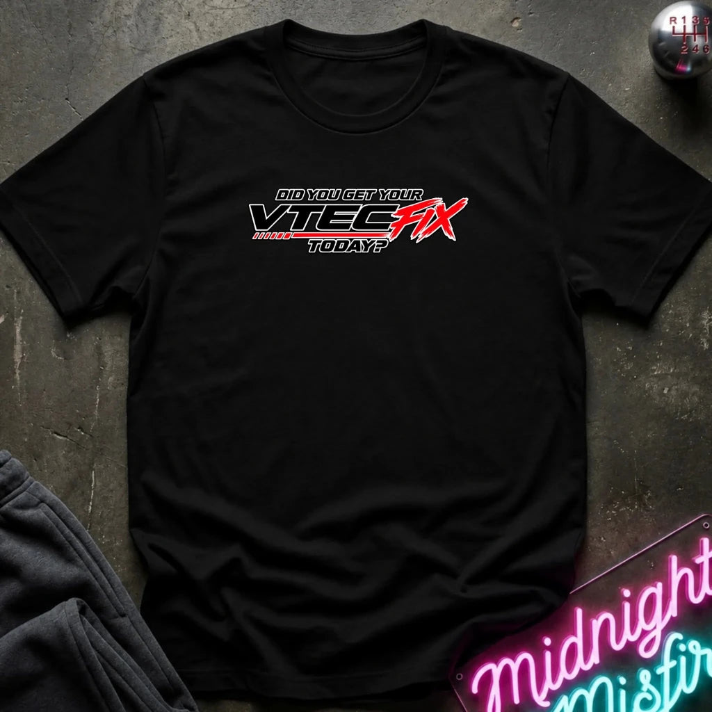 A black short-sleeve t-shirt laid flat on a dark textured surface, featuring a red and white graphic on the chest that reads 'Did YOU GET YOUR VTEC FIX TODAY?' with 'Midnight Misfire' neon sign styling in the corner.