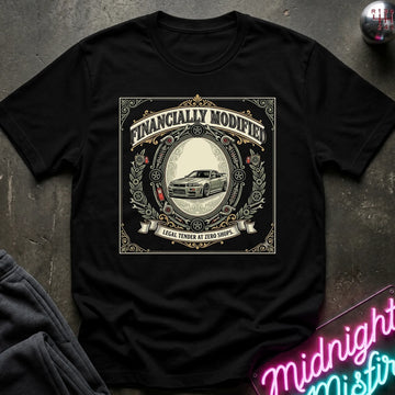A black short-sleeve graphic t-shirt laid flat on a dark textured surface. The shirt features a large vintage-style circular graphic with the text 'FINANCALLY MODIFIED' and 'LOCAL TENDER AT ZERO SHOPS' surrounding an illustration of a classic car.