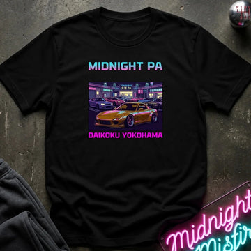 A black short-sleeve graphic T-shirt laid flat on a dark textured surface. The shirt features the text 'MIDNIGHT PA' in a blue-to-pink gradient at the top and 'DAIKOKU YOKOHAMA' in pink at the bottom, surrounding a central graphic of a yellow sports car parked in a neon-lit parking lot.