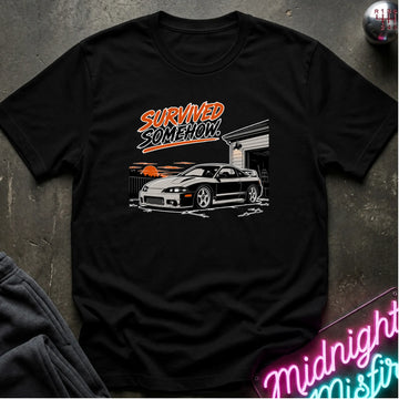 A black short-sleeve graphic t-shirt laid flat on a dark textured surface. The graphic features the text 'SURVIVED SOMEHOW' in orange and white above an illustration of a black sports car in front of a garage with orange sunset clouds.