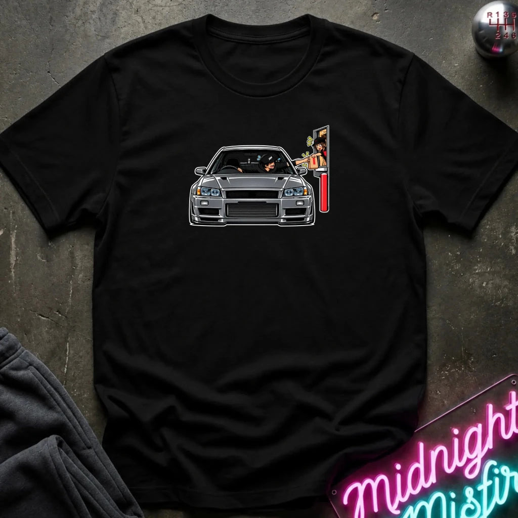 A black short-sleeve t-shirt laid flat on a dark textured surface, featuring a graphic print of a gray sports car with a vertical sign on the chest. 