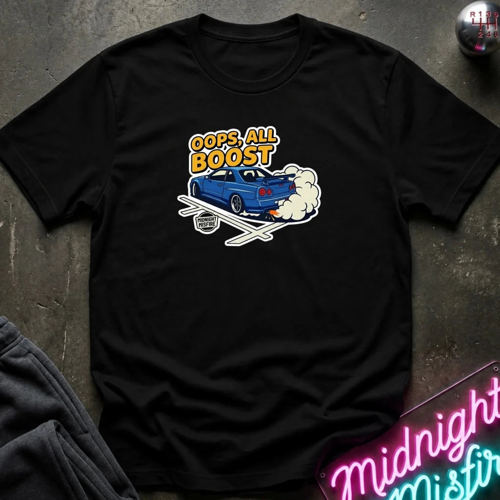 A black short-sleeve graphic t-shirt laid flat on a dark textured surface. The graphic features a blue car with white smoke and the text 'OOPS! ALL BOOST' in yellow and white.