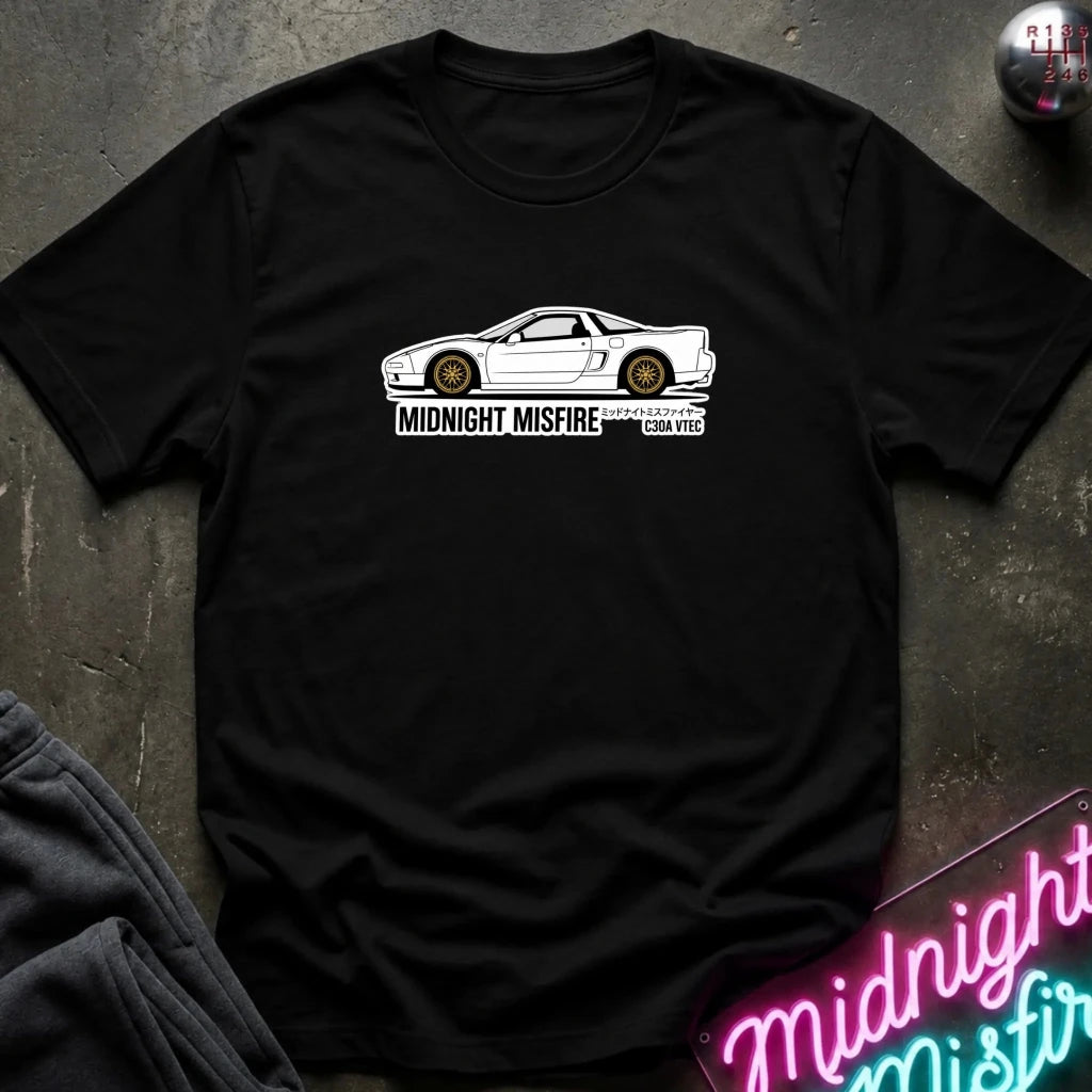 A black short-sleeve t-shirt laid flat on a dark textured surface, featuring a white sports car graphic and the text 'MIDNIGHT MISFIRE '