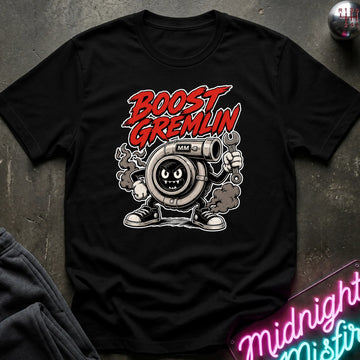 A black short-sleeve graphic T-shirt laid flat on a dark textured surface. The shirt features a large front print with the words 'BOOST GREMLIN' in red and white, above a cartoon turbocharger character in gray, white, and black.