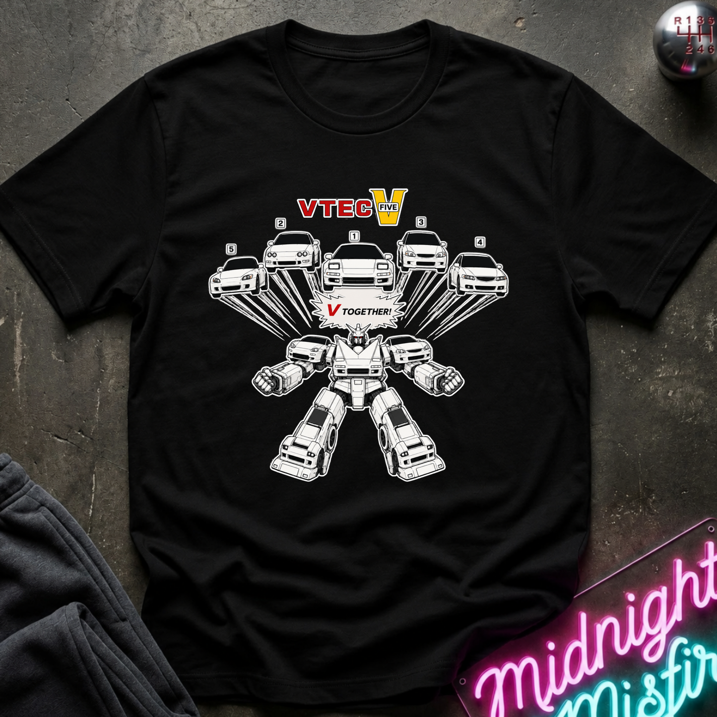 A black short-sleeve graphic T-shirt laid flat on a dark textured surface. The shirt features a white line-art robot made from cars, with the words 'VTECH' in red and yellow above and 'V TOGETHER' in red on the chest.