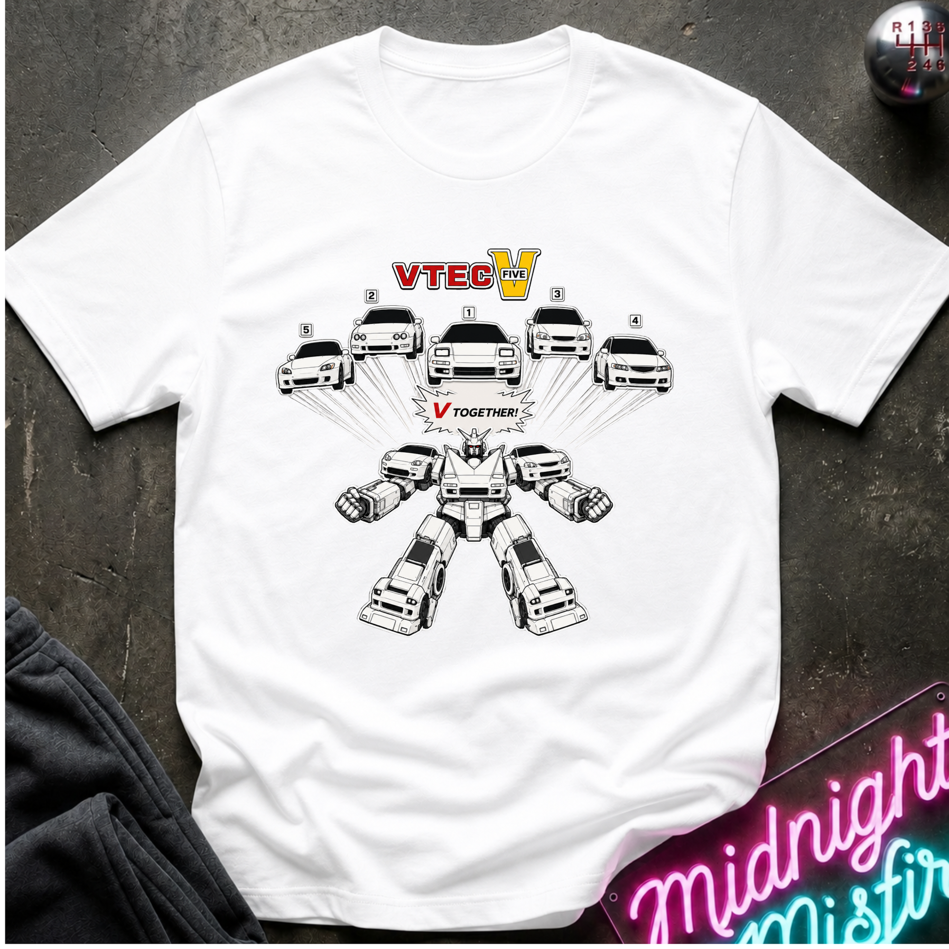 A white short-sleeve graphic T-shirt laid flat on a dark textured surface. The shirt features a black-and-white robot made from cars, with the text 'VTEC V' above and 'TOGETHER' below the robot.