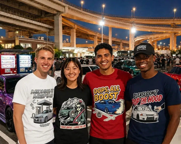 Four people standing together in a parking lot at dusk, each wearing a different graphic T-shirt with car-themed designs and text. Highways and parked cars are visible in the background.