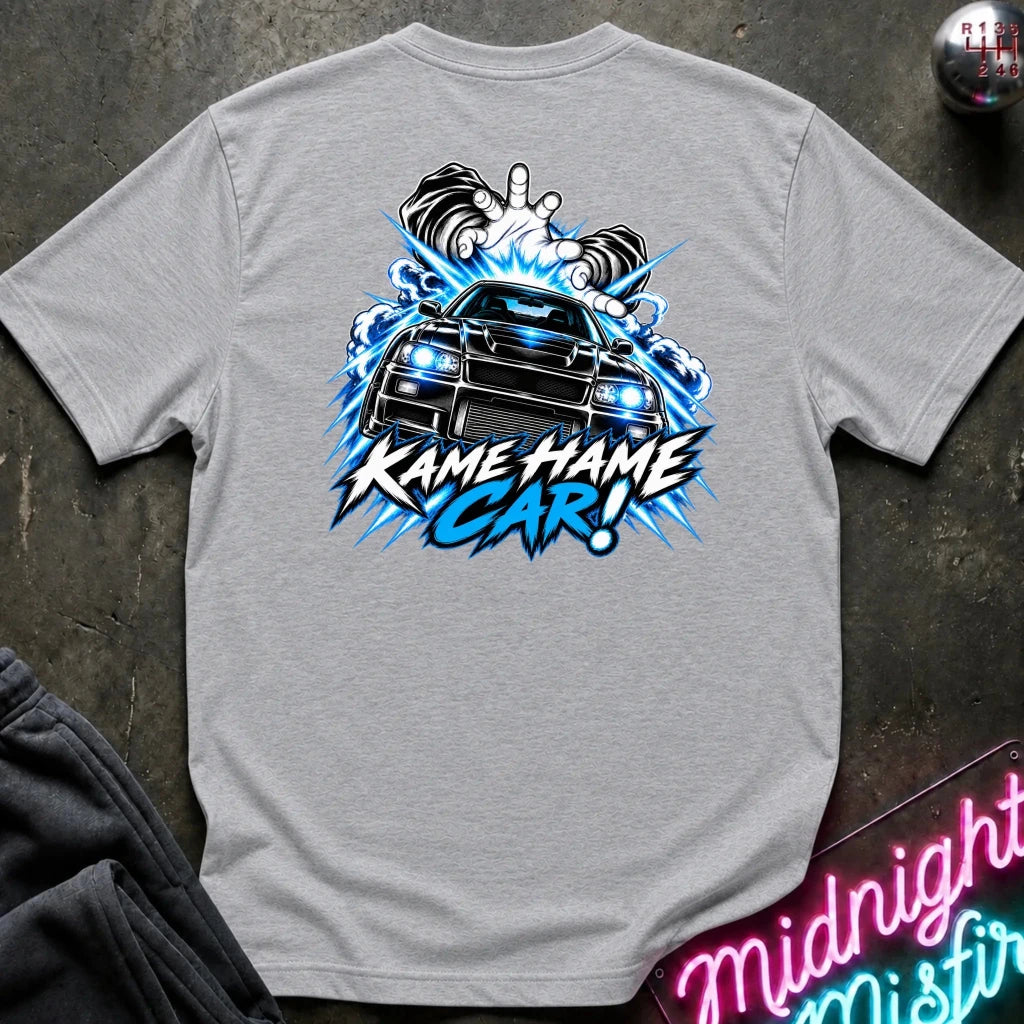 A heather gray t-shirt laid flat on a dark textured surface, featuring a large graphic print on the back of a black car with blue lightning effects and the text 'KAME HAME CAR!'.