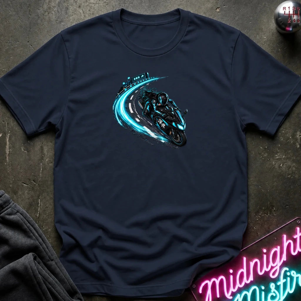 A navy blue short-sleeve t-shirt laid flat on a dark textured surface, featuring a graphic of a motorcycle riding a glowing teal road curve. 