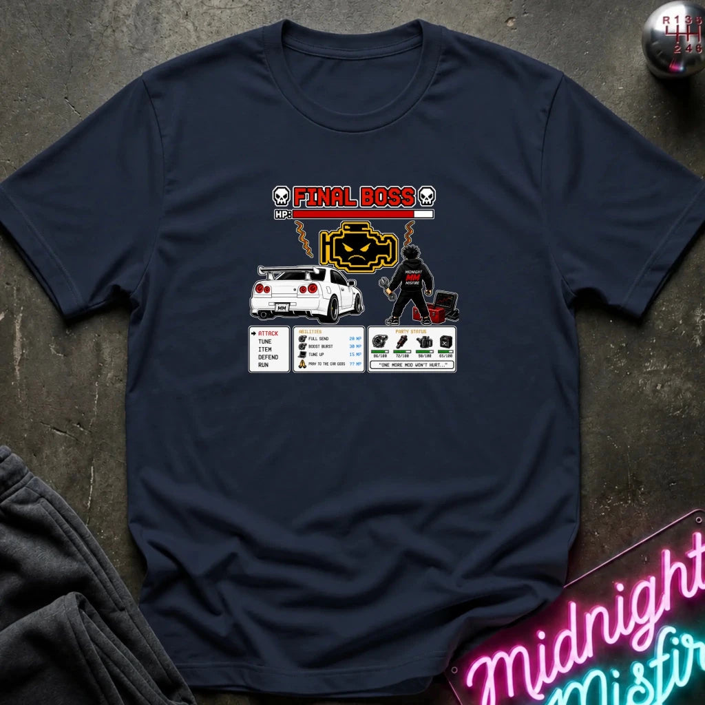 A navy blue graphic t-shirt laid flat on a dark textured surface. The shirt features a 'Final Boss' engine design inspired by the rpg game.