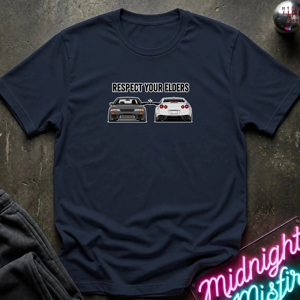navy graphic t-shirt laid flat on a dark textured surface. The graphic features the text and blue car facing a white car.