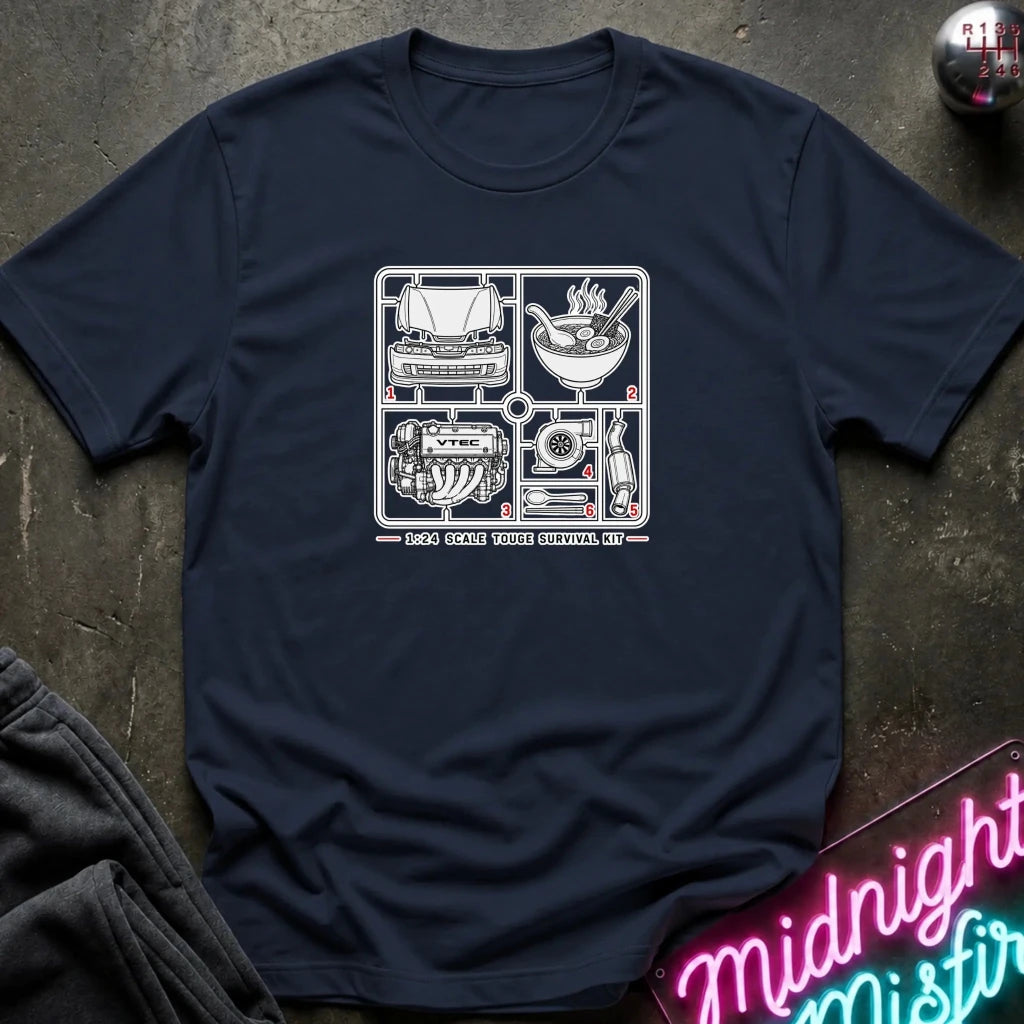 A navy blue crewneck t-shirt laid flat on a dark textured surface, featuring a white graphic print of classic car parts and automotive-themed illustrations 